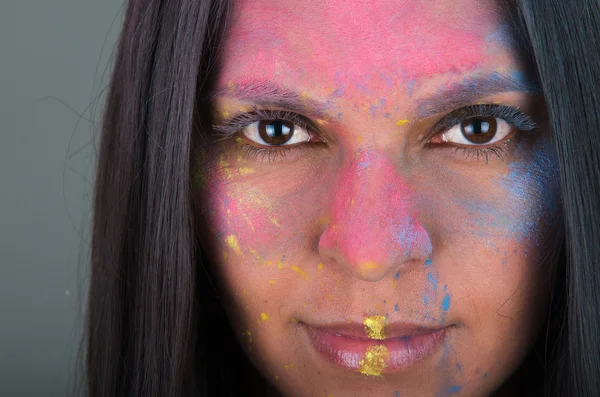 Beautiful young brunette girl with colorful powder painted face