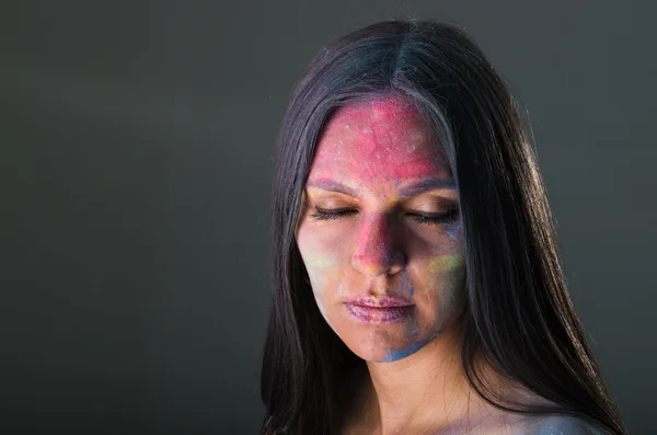 Beautiful young latin girl with colored powder on her face