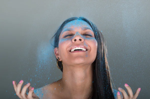 Portrait of beautiful girl as blue powder falls down on her face