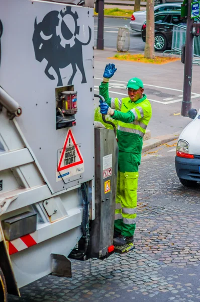 Garbage collector standing on truck, Paris, France