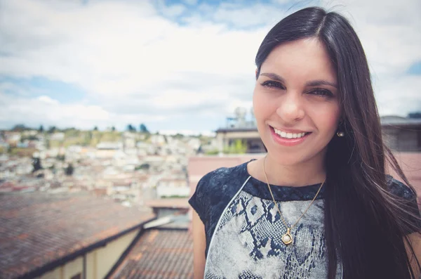 Classy attractive brunette wearing black white dress sitting on rooftop with nice view looking into camera smiling