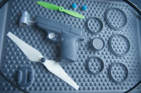 Black rubber rings, toy gun and small propellers lying on plastic bubble surface, print screen process