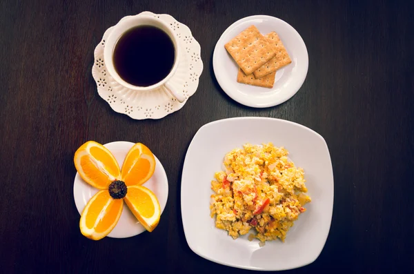 Elegant breakfast concept seen from above, coffee cup, crackers, scrambled eggs, and sliced oranges