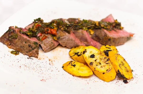 Delicious medallions of tenderloin steak placed upon white dinner plate with some vegetables next to it, elegant presentation