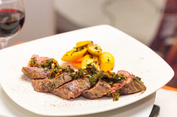 Delicious medallions of tenderloin steak placed upon white dinner plate with some vegetables next to it, elegant presentation