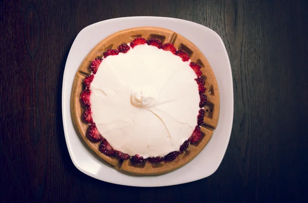 Beautiful small pie covered with wild berries under cream layer, as seen from above, elegant concept
