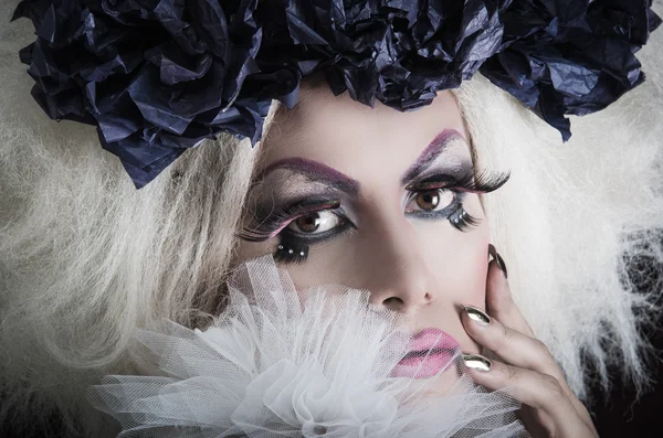 Drag queen with spectacular makeup, glamorous trashy look, posing happily and charming camera from sideways angle