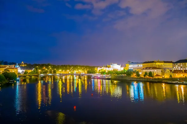 Prague, Czech Republic - 13 August, 2015: Waterfront view of Prague with beautiful lights shining reflective across water, evening sky