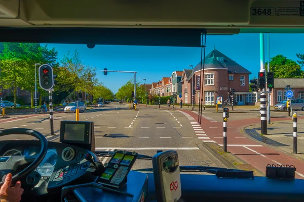 Harlem, Amsterdam, Netherlands - July 14, 2015: Inside public transportation bus in traffic, front seat view, driver on the left, nice sunny day