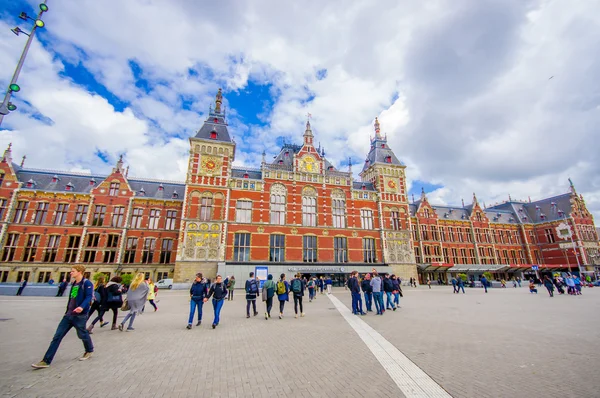 Amsterdam, Netherlands - July 10, 2015: Central station as seen from outside plaza, beautiful traditional European facade with classic clock tower