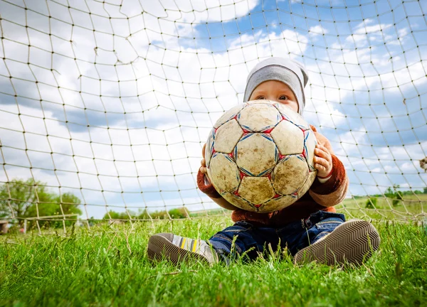 The baby in a cap plays with a ball