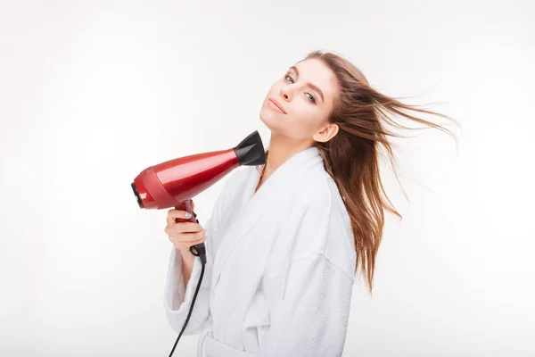 Beautiful sensual young woman in bathrobe drying hair with dryer