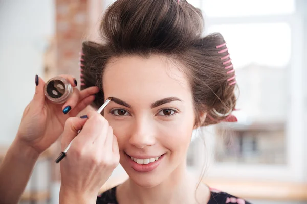 Makeup artist doing makeup to woman with curlers