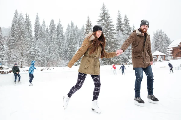 Portrait of a smiling couple ice skating outdoors