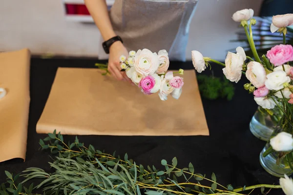 Hands of female florist creating bouquet on black table