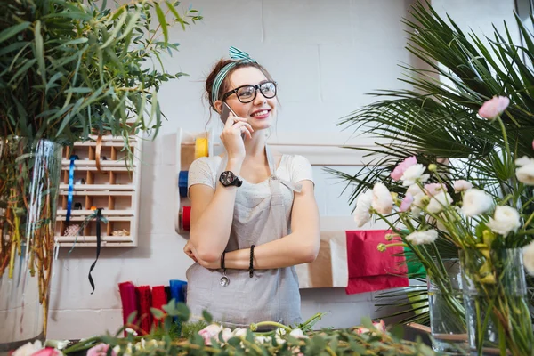 Woman florist talking on mobile phone in flower shop