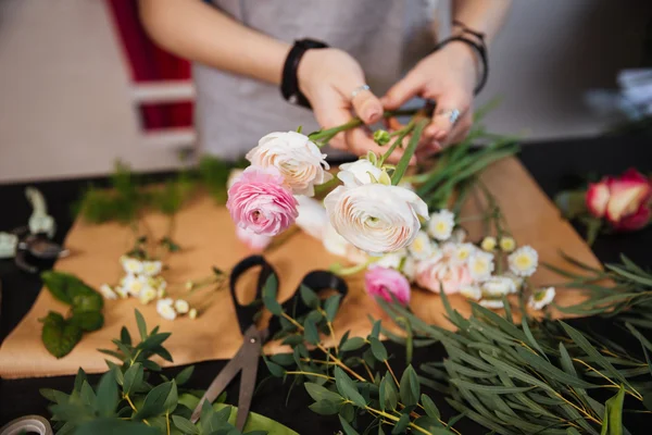 Hands of woman florist creating bouquet with pink roses