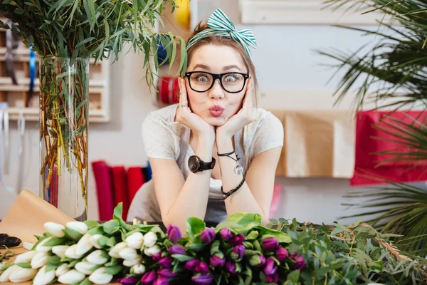 Amusing woman florist making funny face standing in flower shop