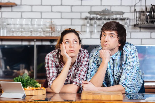 Pensive couple thinking on the kitchen
