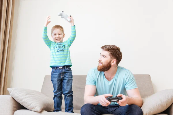 Happy little boy playing computer games with dad and winning