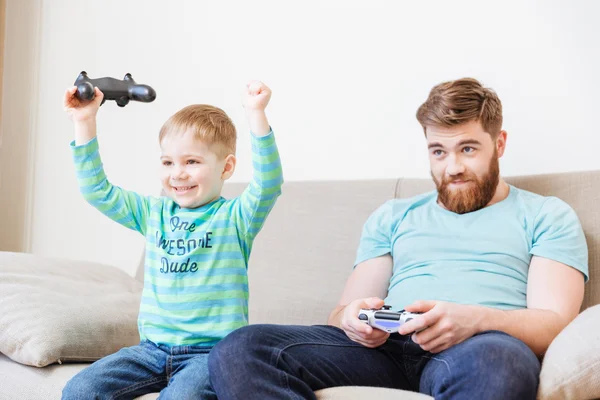 Little son playing computer games with father and winning