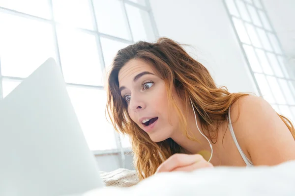 Amazed woman using laptop computer on the bed