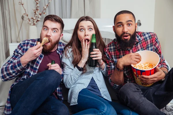 Frightened shocked people drinking beer and watching tv