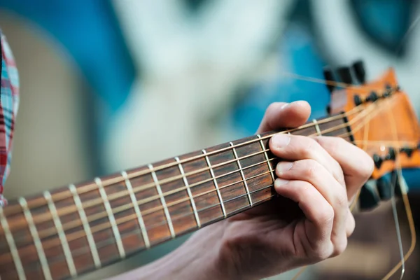 Male hands playing on guitar outdoors