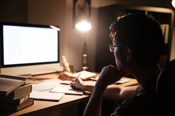 Man in glasses sitting and using computer for studying