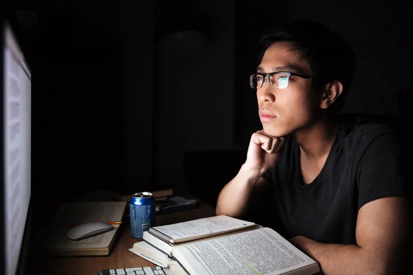 Serious asian man studying with books and computer