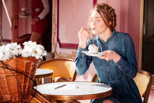 Relaxed woman sitting and eating cupcake in outdoor cafe