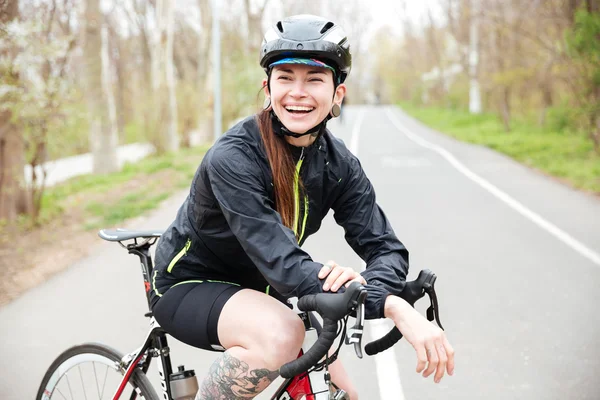 Happy beautiful young woman in bicycle helmet on bike