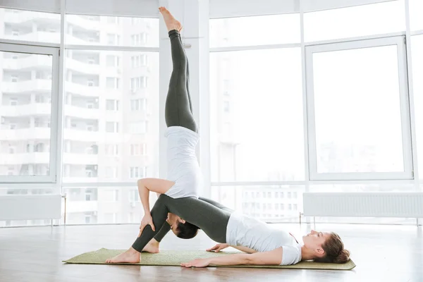 Two women doing balancing pose on pink yoga mat