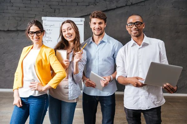 Group of cheerful business people with tablet and laptop