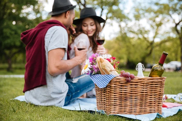 Basket with food and drinks standing near couple in park