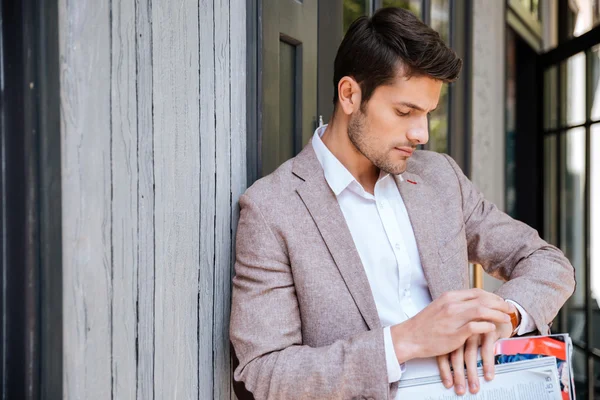 Close-up portrait of man looking at his watch outdoors