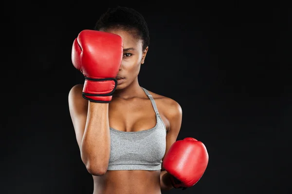 Strong young fitness woman covered her face with boxing gloves