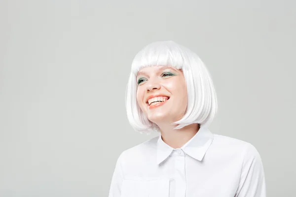 Happy attractive young woman in blonde wig standing and laughing