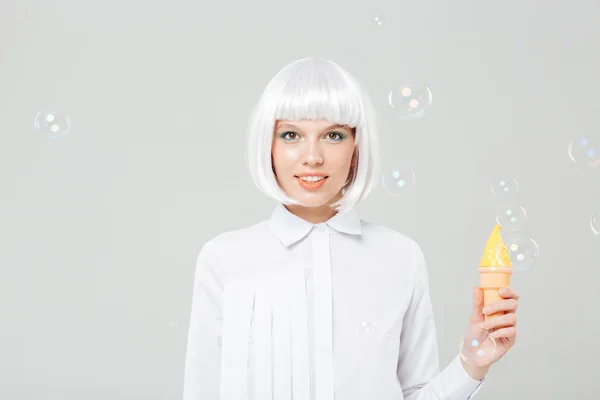 Smiling young woman in blonde wig holding fake ice cream