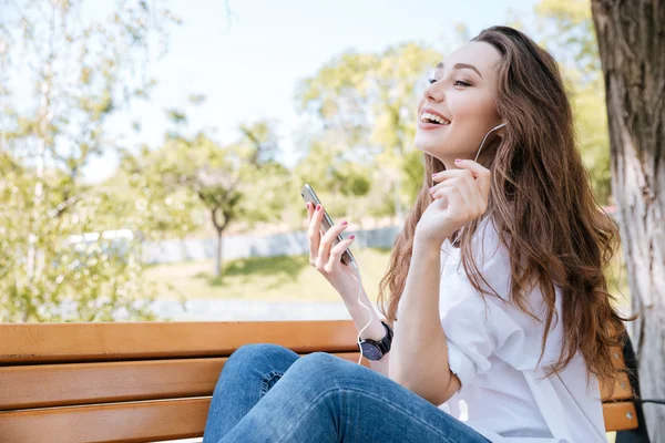 Portrait of a smiling girl with earphones listening music outdoors