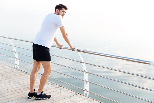Man athlete resting after running standing on pier