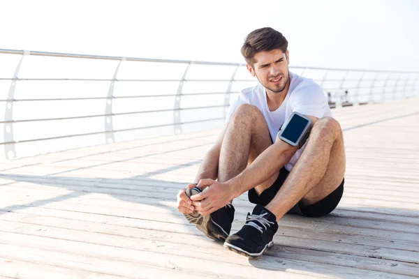 Exhausted young sportsman tired after running sitting outdoors