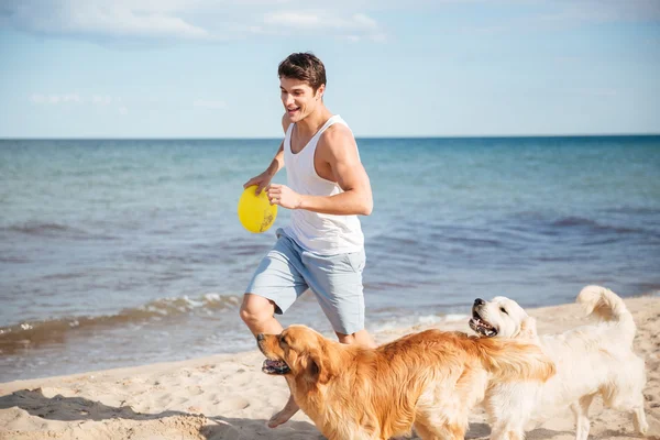 Athletic handsome man playing with his dog on the beach