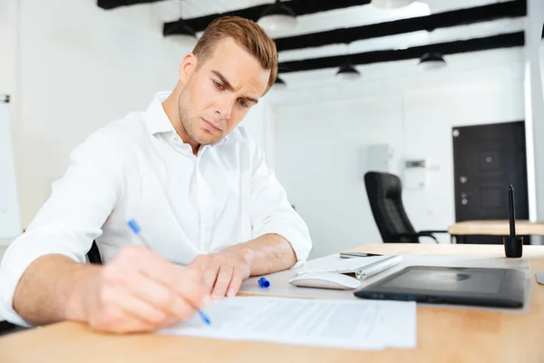 Businessman sitting in office and writing