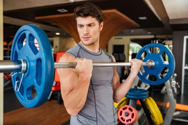 Man athlete working out with barbell in gym