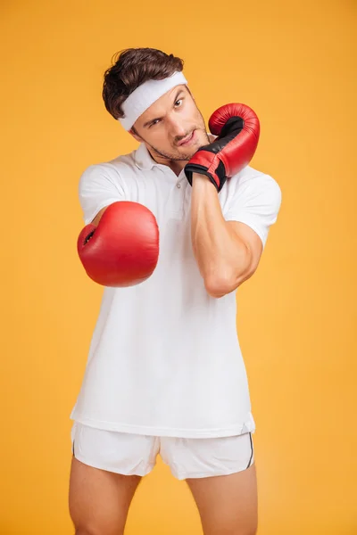 Aggressive young man boxer in red gloves warming up