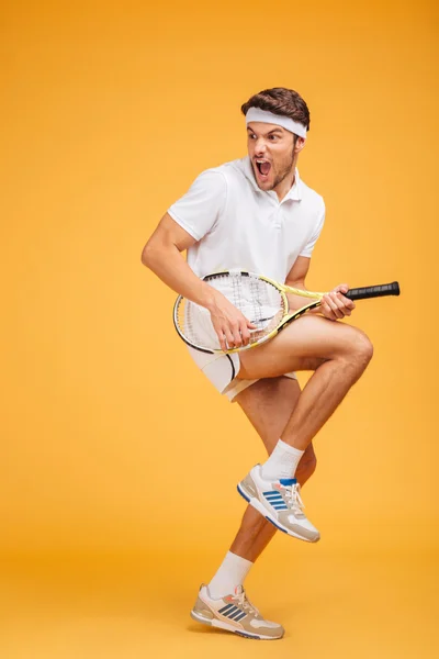 Comical young man tennis player with racket shouting and joking