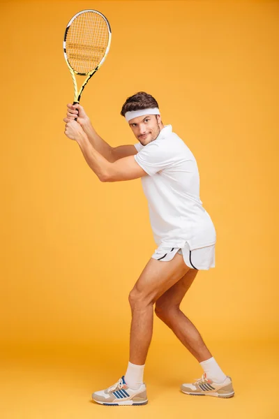 Full length of attractive man player standing and playing tennis