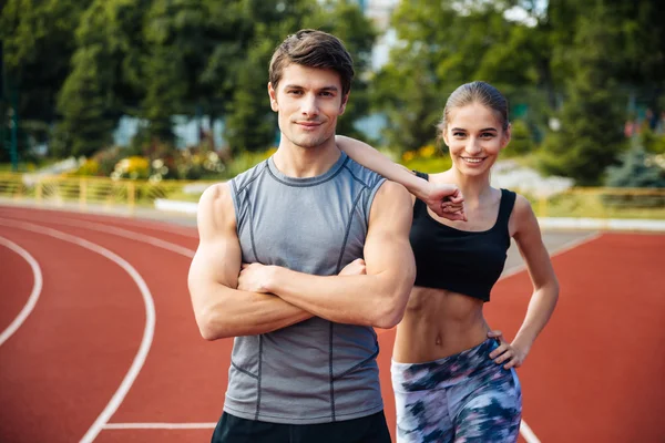Young man and woman standing on athletics race track