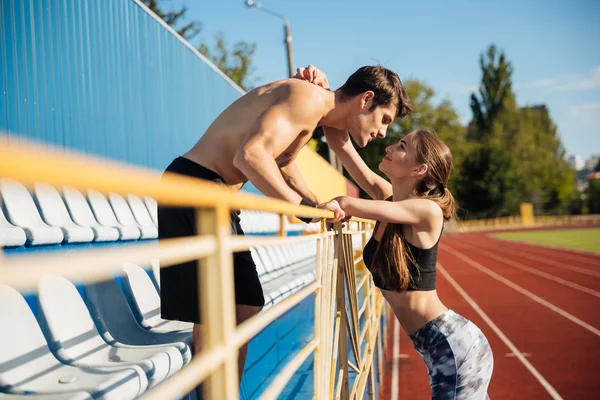 Sports couple in love hugging on athletics track field
